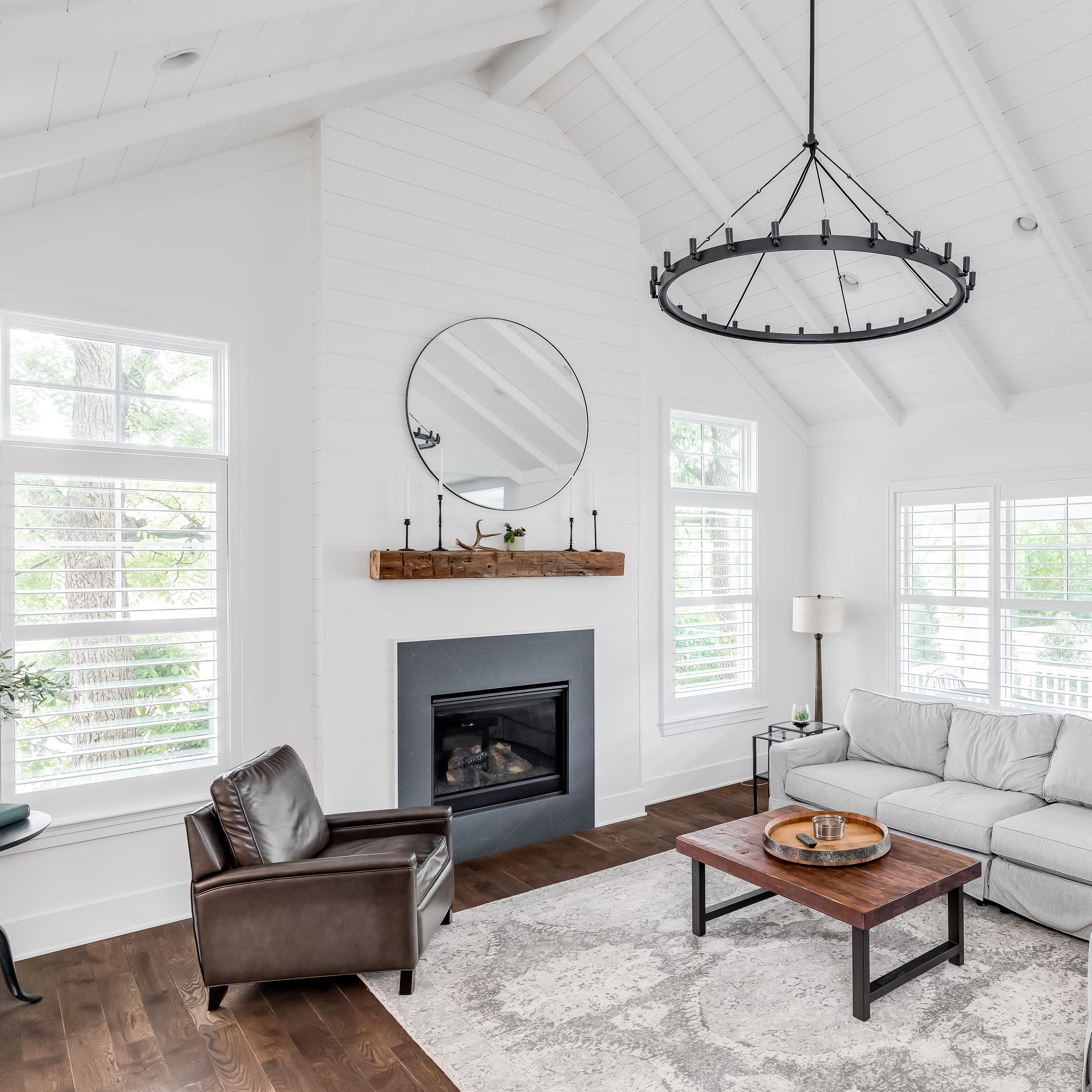 farmhouse living room with shiplap, white beams, and chandelier.