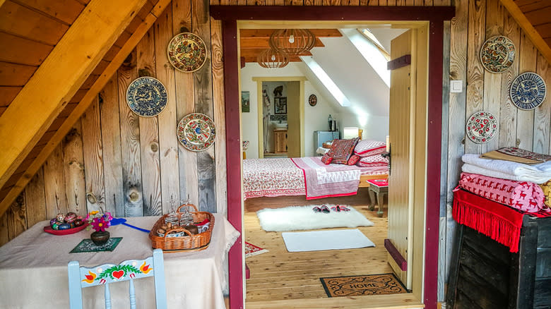 Traditional art interior decoration with a view from the kitchen and dining area, and a door leading to the bedroom. Traditional paintings, decorative plates on the walls, and flower beds are included.