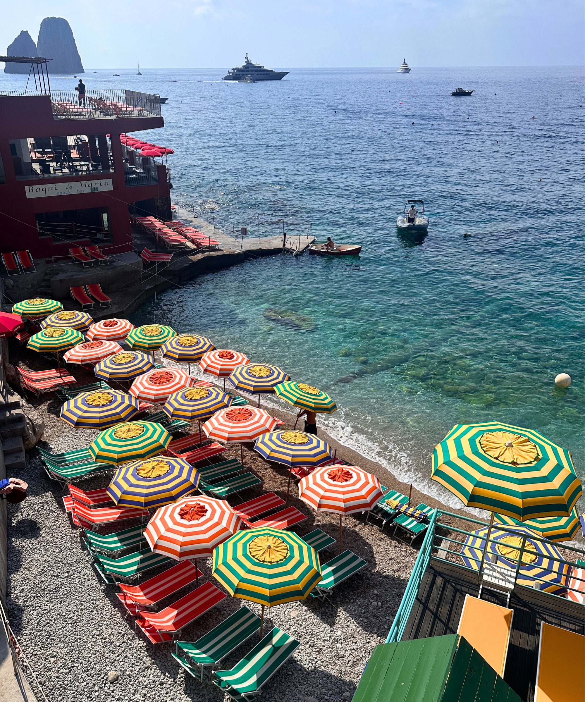 bagni internazionali capri on the beach with colorful umbrellas and sunloungers overlooking the famous rocks of capri