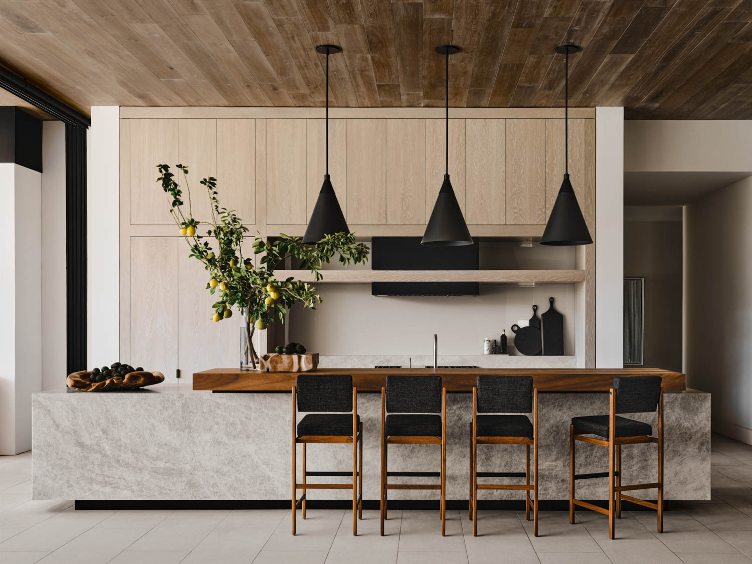 Kitchen with black stools and black pendant lights above the island