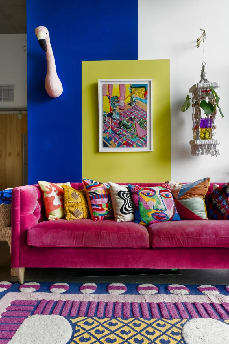 A blue, green, and white wall with a faux taxidermy flamingo and a pink sofa