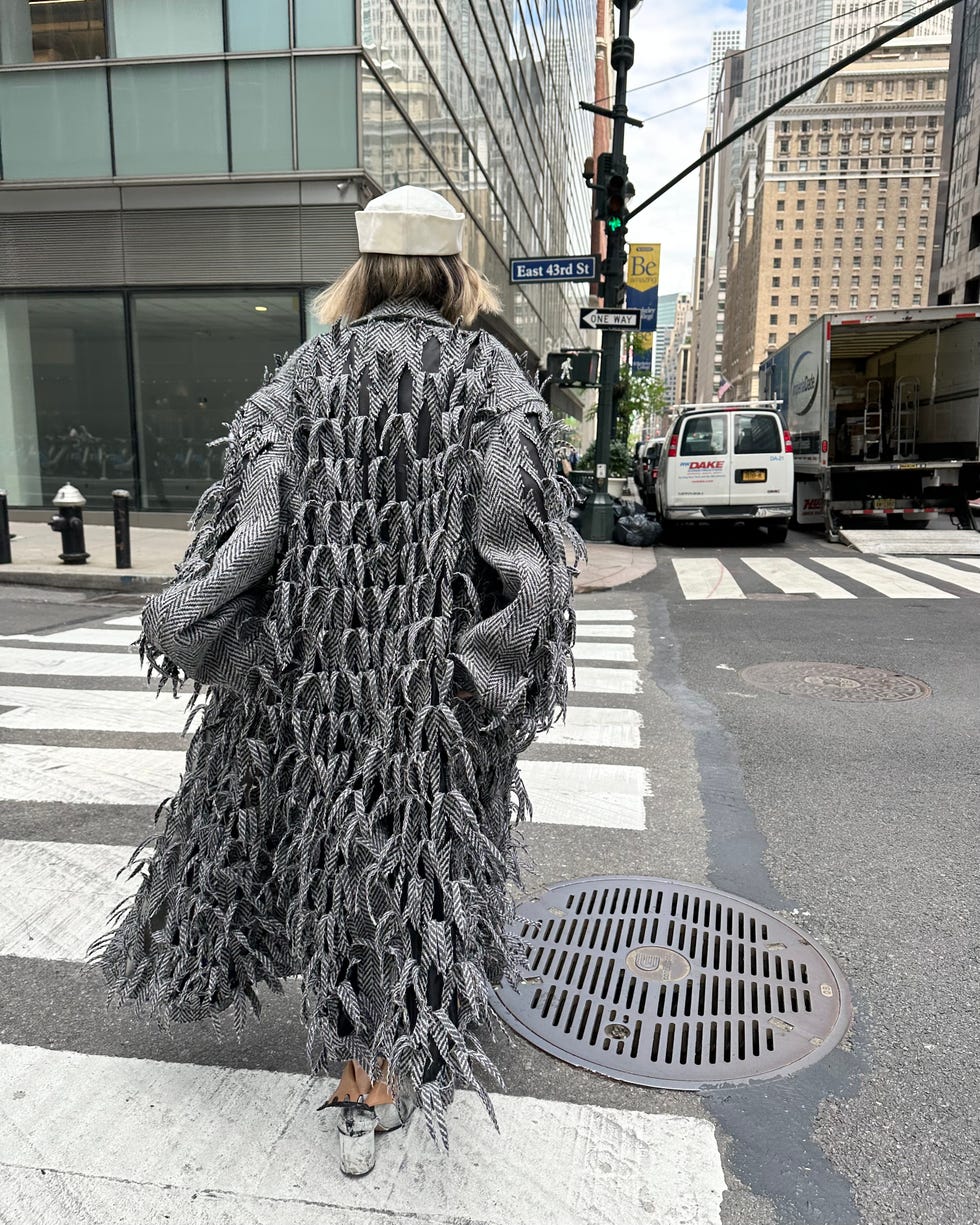 A person crossing the street wearing a unique coat, showing the urban environment.