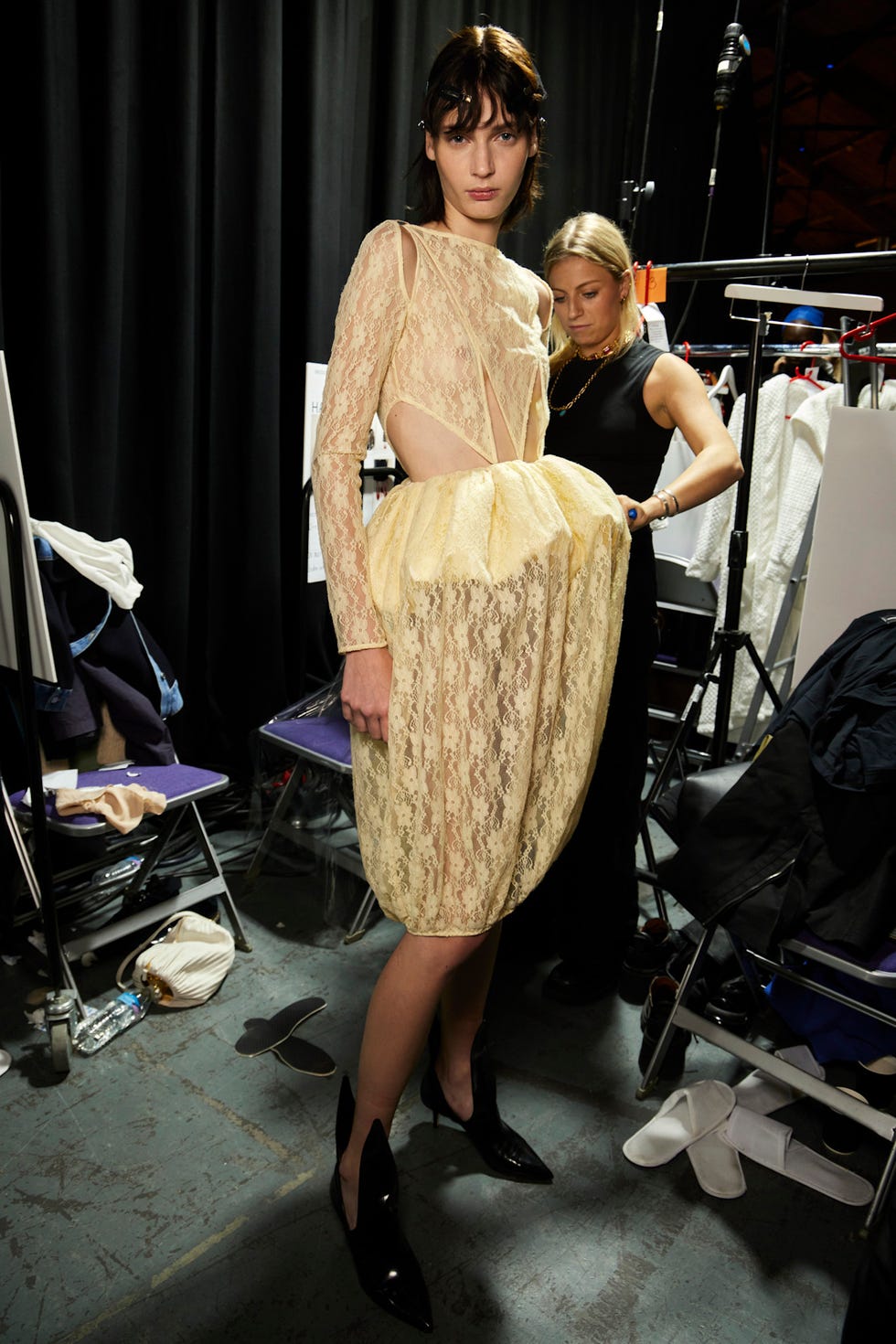 A model wearing a lace dress and high heels during a fashion event.