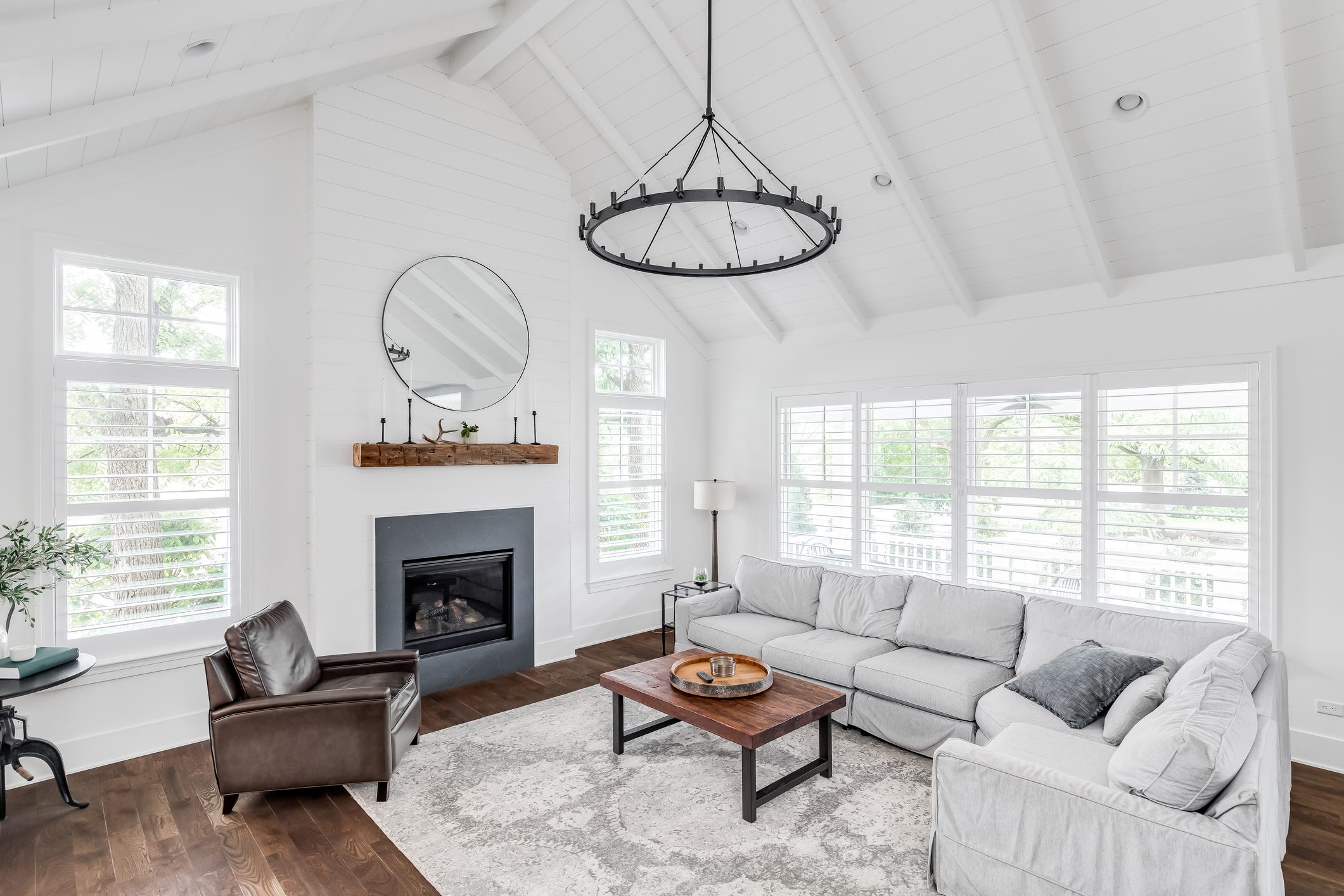 modern farmhouse living room with shiplap, exposed white beams, fireplace and hardwood furniture.