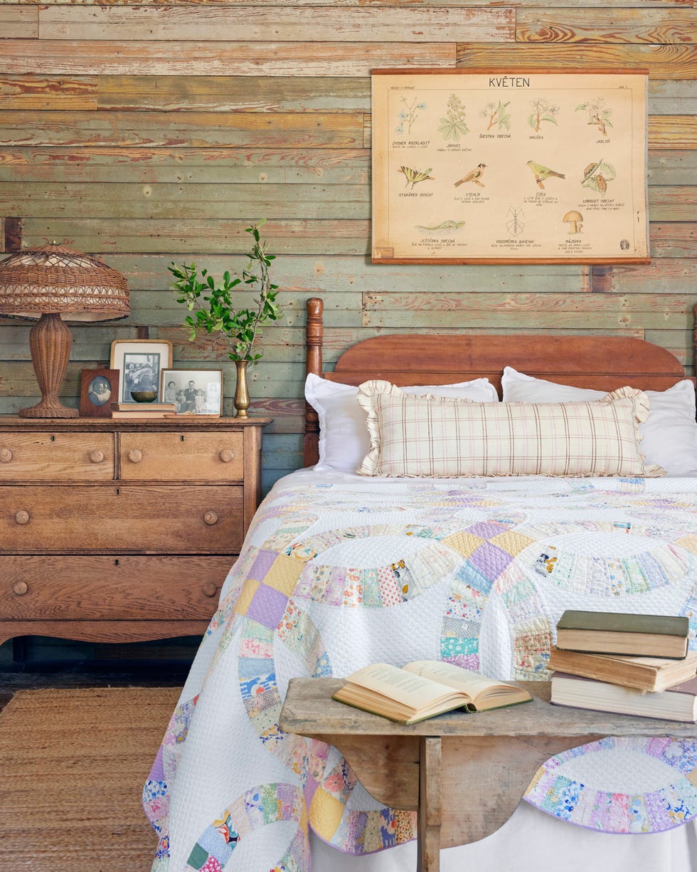 guest bedroom with exposed wood walls and colorful wedding ring fabric at the end of the bed