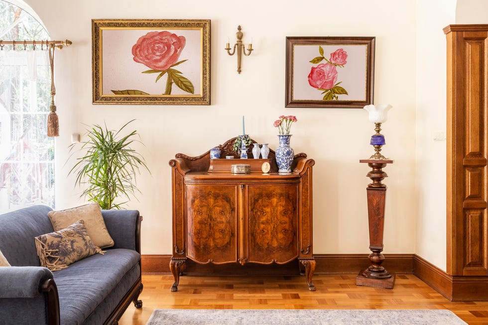 real photo of antique cabinet with porcelain ornaments, rose paintings and blue sofa in living room.